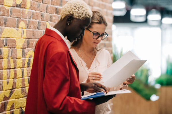 Duas profissionais de marketing analisando documentos de estratégia, representando o serviço de CMO as a Service da A Estranhamente